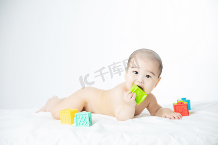可爱婴儿人物摄影照片_婴儿白天玩玩具的婴儿室内趴在床上摄影图配图