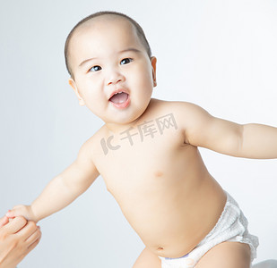 童趣摄影照片_婴儿母婴白天站起来的小男婴室内张嘴笑摄影图配图