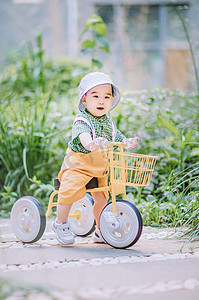 宝宝启蒙摄影照片_婴儿白天可爱男孩室内骑小车摄影图配图