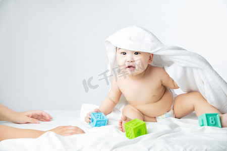 儿童宝宝成长摄影照片_婴儿白天玩玩具的男婴室内床上坐着摄影图配图