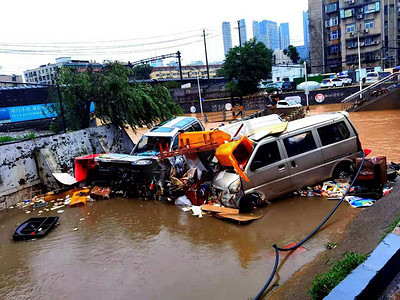 台风暴雨摄影照片_抗洪防汛暴雨后损坏的城市道路车辆摄影图配图