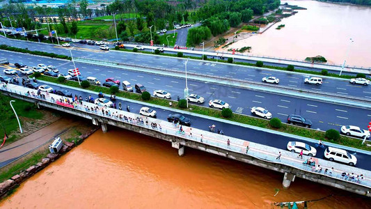 台风摄影照片_河南郑州洪水内涝洪水流过大桥摄影图配图
