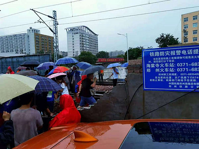 洪涝摄影照片_暴雨洪涝灾害后的居民撑伞等待救援摄影图配图