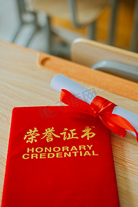 红课摄影照片_荣誉证书毕业季红色证书课桌上平放着摄影图配图