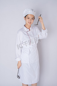 年轻女厨师白天一个女厨师白背景上拿勺子喝汤摄影图配图