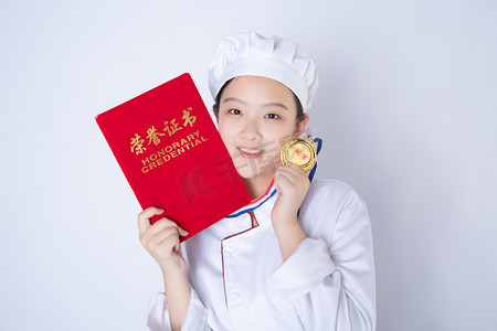 年轻女厨师白天一个女厨师白背景拿着证书奖牌靠近脸摄影图配图