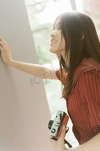 文艺墙摄影照片_夏日文艺人像白天长发美女校园里扶墙开心笑摄影图配图
