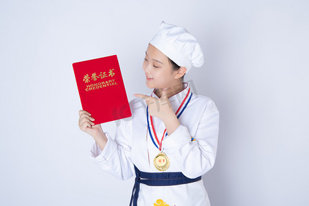 年轻女厨师白天一个女厨师白背景手指着荣誉证书摄影图配图