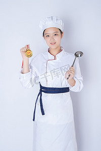 冠军季奖牌摄影照片_年轻女厨师白天一个女厨师白背景一手拿奖牌一手拿勺子摄影图配图