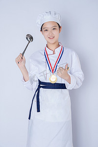 年轻女厨师白天一个女厨师白背景戴着奖牌拿着勺子点赞摄影图配图