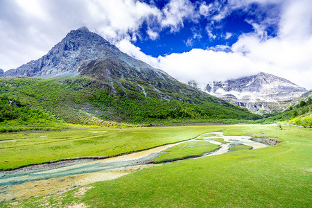 高原山地图竖屏摄影照片_稻城亚丁白天雪山河流高原风光蓝天白云草地摄影图配图