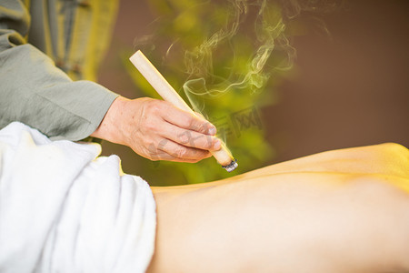 礼遇女人节摄影照片_中医养生白天中医理疗的女人室内背部艾灸摄影图配图