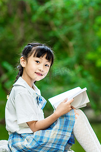 女生感觉疼痛摄影照片_人物白天小女生草地上看书摄影图配图