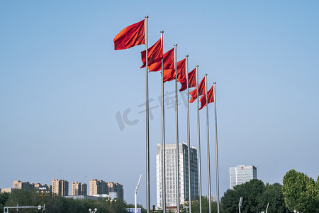 国庆节旗帜摄影照片_户外迎风飘扬的红色旗帜摄影图配图