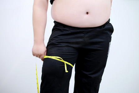 肥胖青少年用尺子测量大腿努力减肥摄影图配图