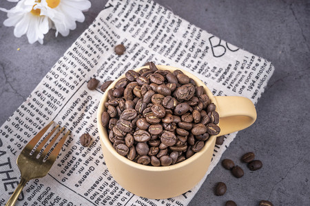 黄色咖啡杯中满满的咖啡豆食材摄影图配图