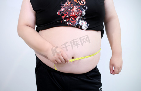 尺子与圆规摄影照片_用尺子测量肚子的青少年肥胖特写摄影图配图