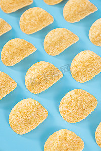 油炸食品摄影照片_薯片零食油炸食品蓝色创意背景摄影图配图
