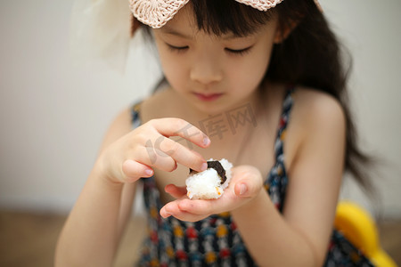 室内可爱的小女孩用手托着寿司特写摄影图配图