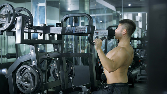 运动器材水彩摄影照片_健身教练男性锻炼大型器材背部训练健身运动