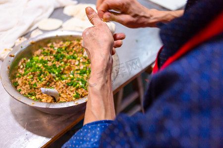 美食包子摄影照片_早餐店厨师包包子上午一个人室内包包子摄影图配图