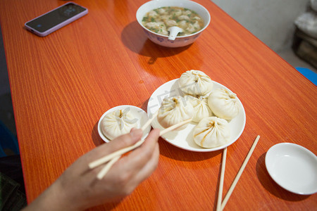 包子店摄影照片_吃早餐上午一个人室内吃早餐摄影图配图