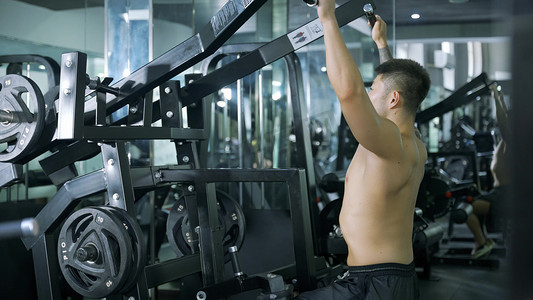 线条流汗摄影照片_健身教练男性锻炼大型器材背部训练