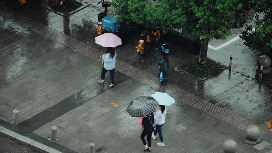 雨中撑伞摄影照片_雨中撑伞的行人下大雨雨天场景实拍