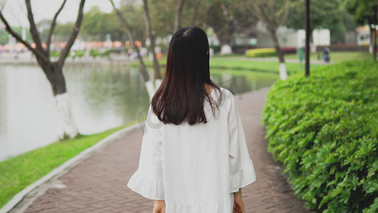 美女走在公园路上散步背影