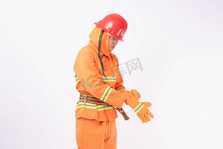 消防手套摄影照片_消防白天男消防员室内戴手套摄影图配图