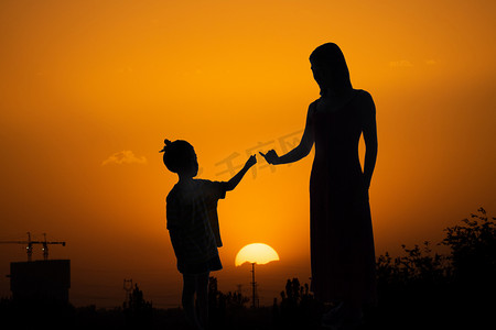 简单人像剪影摄影照片_人像剪影夕阳母女二人在夕阳下拉勾勾摄影图配图