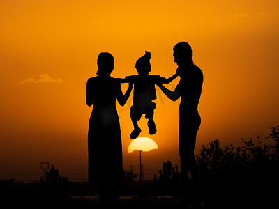 有摄影照片_人像剪影夕阳一家三口夕阳下父母抬起孩子摄影图配图