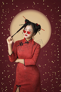 新年签喜庆海报摄影照片_国潮复兴白天穿旗袍的美女室内把扇子放在额头摄影图配图