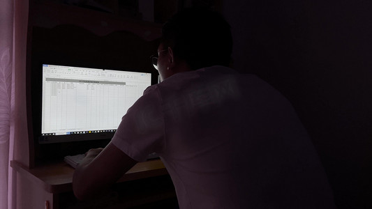 实拍深夜灯光下伏案工作的背影