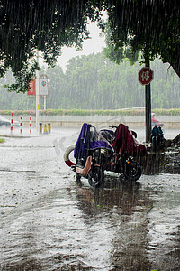 暴雨摄影照片_白天户外电动车在暴雨下停驻摄影图配图