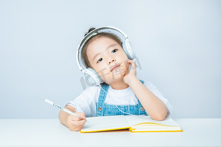 可爱小学生思考摄影照片_线上教育白天上网课的小女孩室内托腮思考摄影图配图