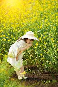 开业主画面摄影照片_低头闻油菜花香的小女孩唯美清新的画面摄影图配图