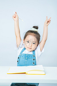小女孩白天做作业的小女孩室内双手举高摄影图配图