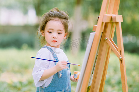 儿童节摄影照片_儿童美术白天可爱小女孩户外草坪写生画画摄影图配图人物