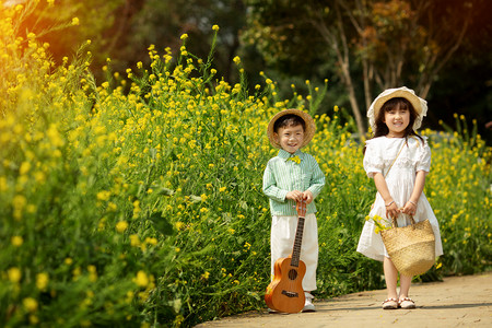 开心的女孩子摄影照片_手拿吉他的小男孩和手拿提篮的小女孩摄影图配图