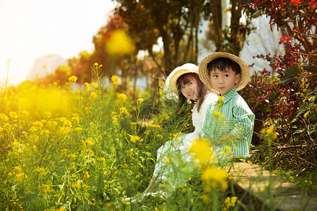 可爱孩子的摄影照片_兄妹在油菜花地玩耍开心的笑摄影图配图