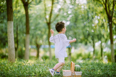 透明泡泡ps摄影照片_童趣白天小男孩户外树林奔跑摄影图配图
