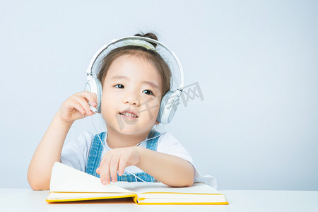 小小学生摄影照片_线上教育白天上网课的小女孩室内手拿耳机摄影图配图