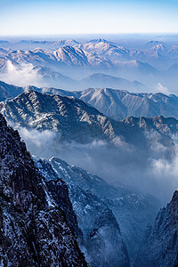 雪摄影照片_冬日旅游晨曦山峰山区飘动摄影图配图