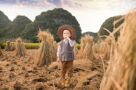 男孩子摄影照片_大山前水稻田里开心的男孩子摄影图配图