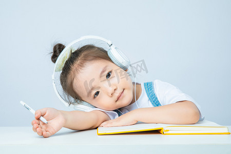 鸟趴在鸟窝里摄影照片_线上教育白天小女孩室内趴在桌子上摄影图配图