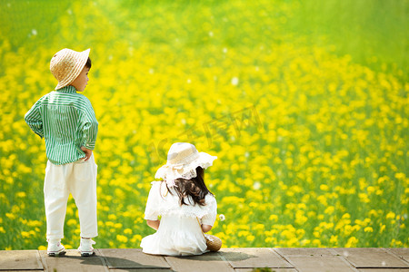 宝宝摄影照片_可爱的宝宝在油菜花田玩耍的唯美背影摄影图配图