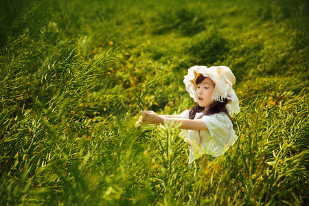 清新女生摄影照片_手捧油菜花的可爱的自爱的小女生摄影图配图