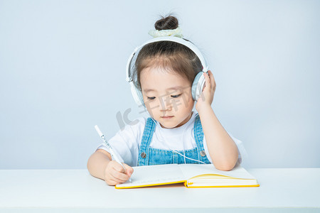 补习班开课摄影照片_小女孩白天上网课的小女孩室内上网课写作业摄影图配图