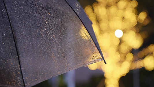 雨滴摄影照片_夜晚灯饰下透明雨伞雨滴滑落意境